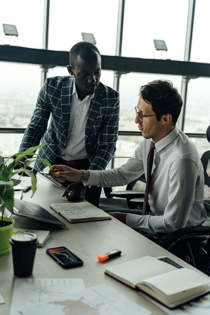 pexels photo 5583974 Two businessmen discussing projects in a modern high-rise office setting.
