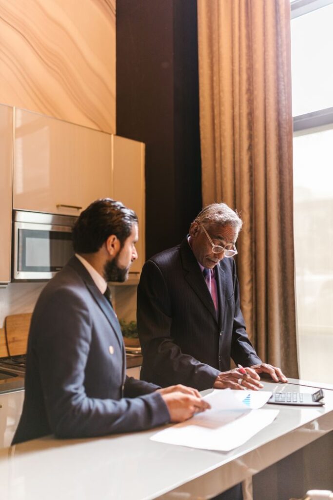 pexels photo 8068656 Two businessmen in suits collaborating over documents in a contemporary office setting.
